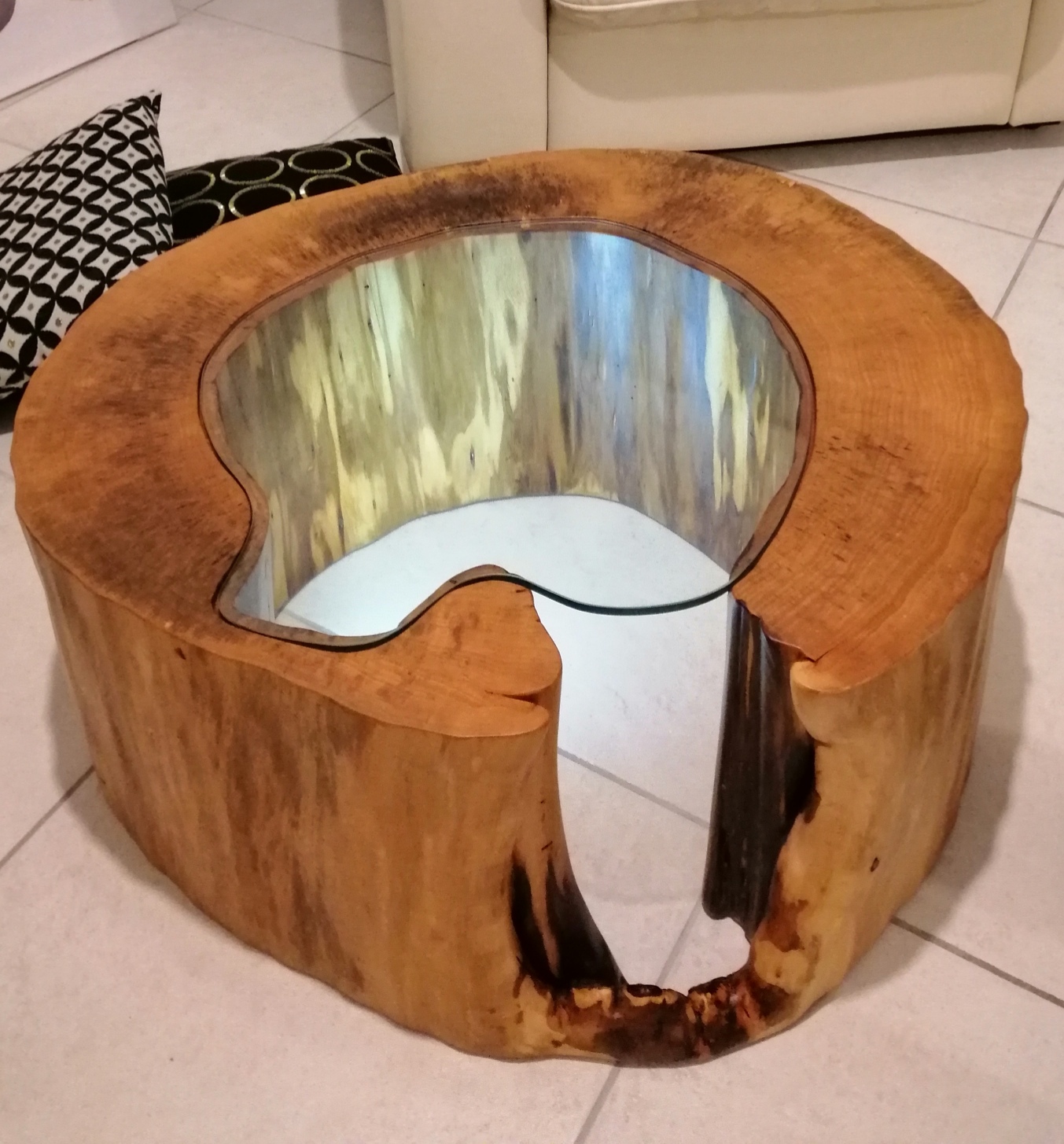 A wooden table made from a trunk of an ancient oak and a tempered glass resting on it. A simple but elegant style makes it unique.